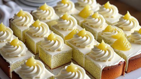 A 9-inch square lemon poppyseed cake, cut into 36 even pieces, each topped with a swirl of creamy white cream cheese frosting piped in a gentle dome, and finished with a delicate sprinkling of lemon zest.  The cake should be presented from 