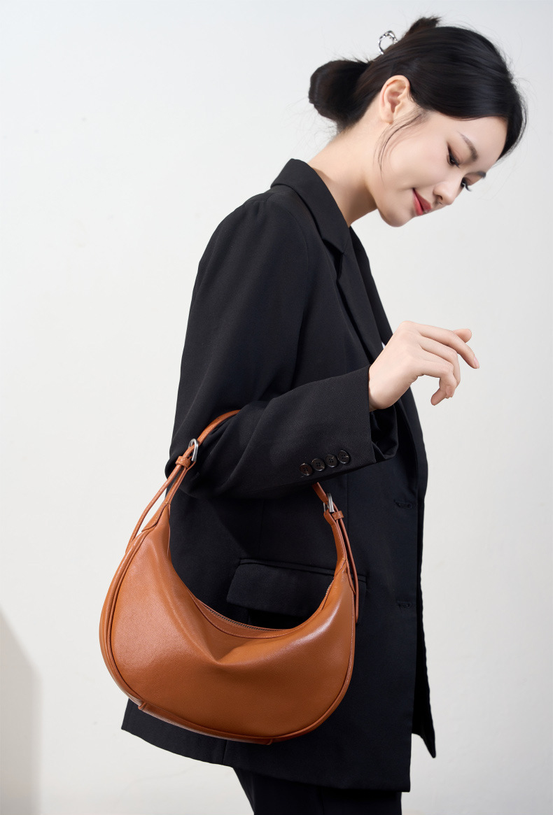 Model carrying Luna Leather Hobo Bag in Caramel – top handle style