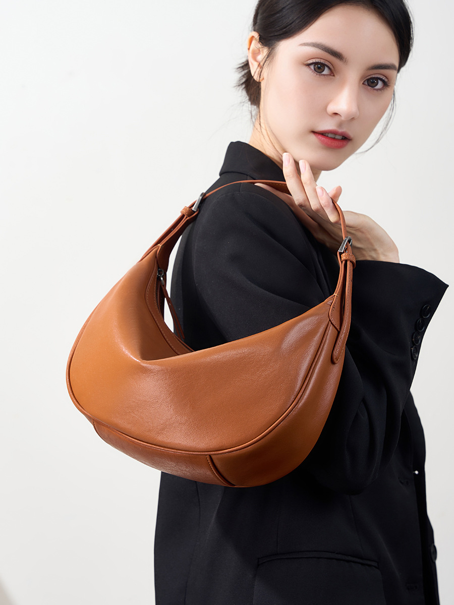 Model carrying Luna Leather Hobo Bag in Caramel – top handle style