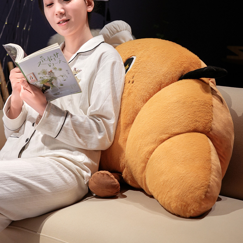 Croissant plush pillow used as a soft bed backrest cushion, croissant-shaped pillow providing comfortable support for relaxing and reading