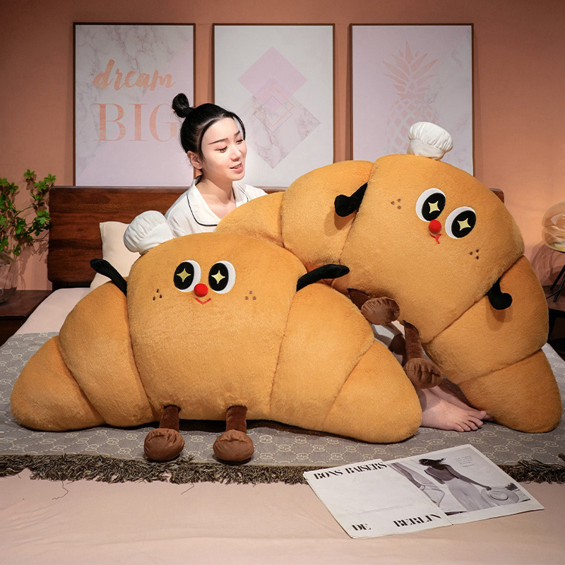 Croissant plush pillows used as cozy bed backrest cushions, soft croissant-shaped pillows for relaxing and lounging in the bedroom
