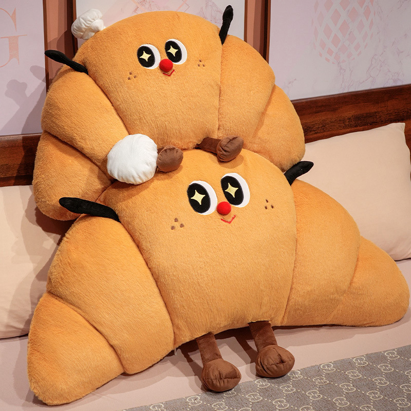 Stacked croissant plush pillows with cute smiling face design, soft croissant-shaped cushions made from plush fabric