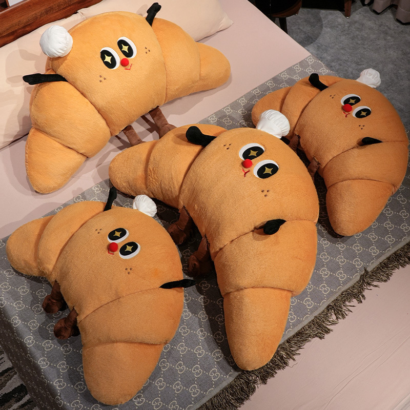 Multiple croissant plush pillows arranged on a bed, soft croissant-shaped cushions with cute face design for cozy bedroom decor