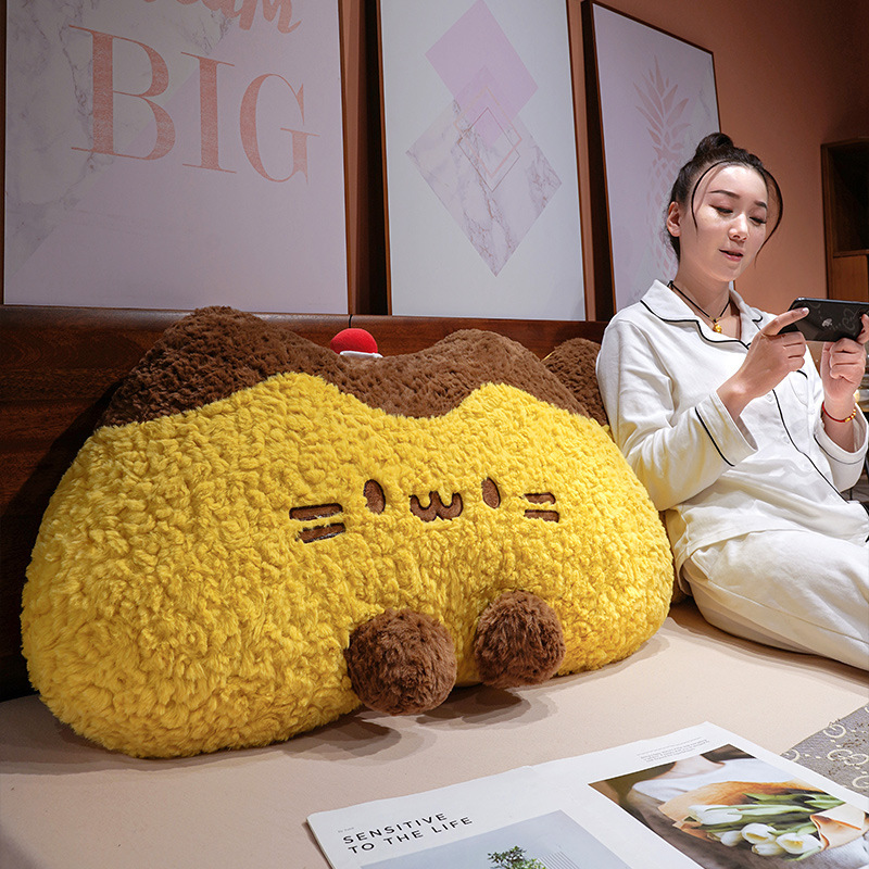 Pudding cat plush backrest pillow on a bed headboard, fluffy pudding cat cushion providing soft support for relaxing and reading in a cozy bedroom