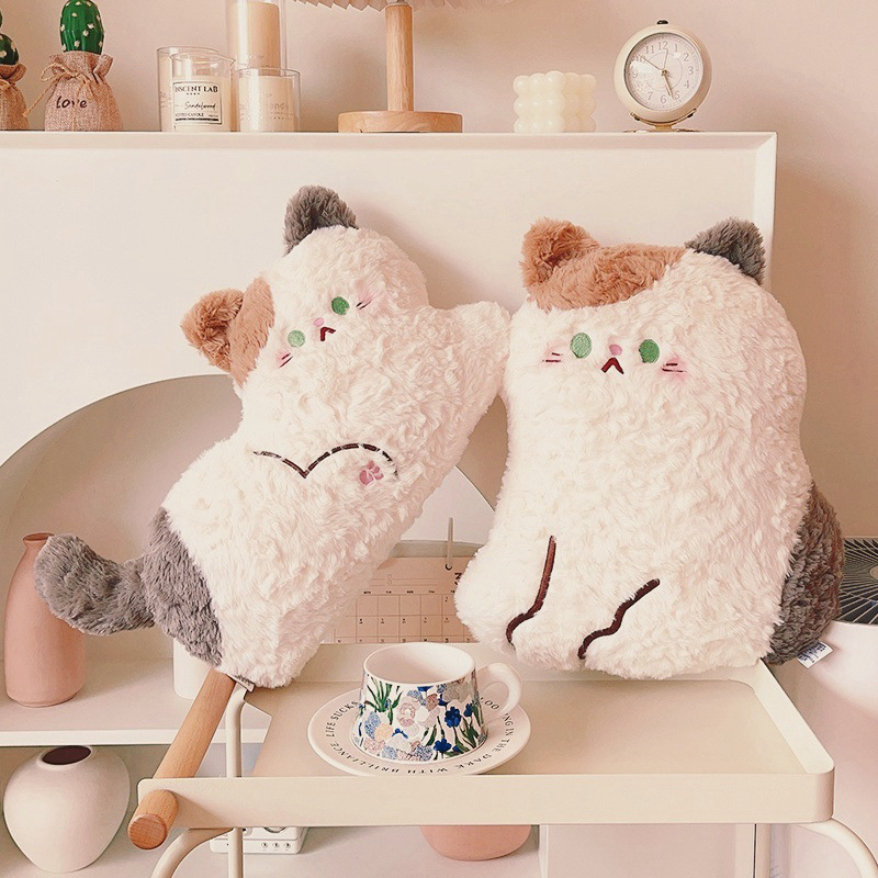 Cute calico cat plush pillows in sitting and lying styles displayed on a shelf, soft fluffy stuffed cushions adding a warm and cozy decorative touch to home spaces