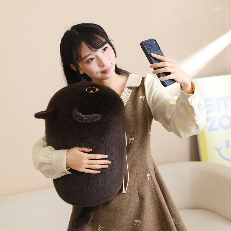 Brown bread cat plush pillow with round loaf-cat shape and fluffy texture, soft hugging cushion for relaxing on a sofa and cozy home decor