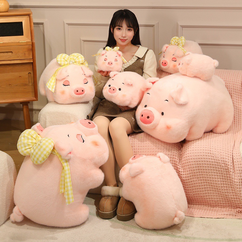 Fluffy pig plush toys in multiple sizes with soft pink fur and yellow bow details, cute stuffed pigs arranged on a cozy sofa