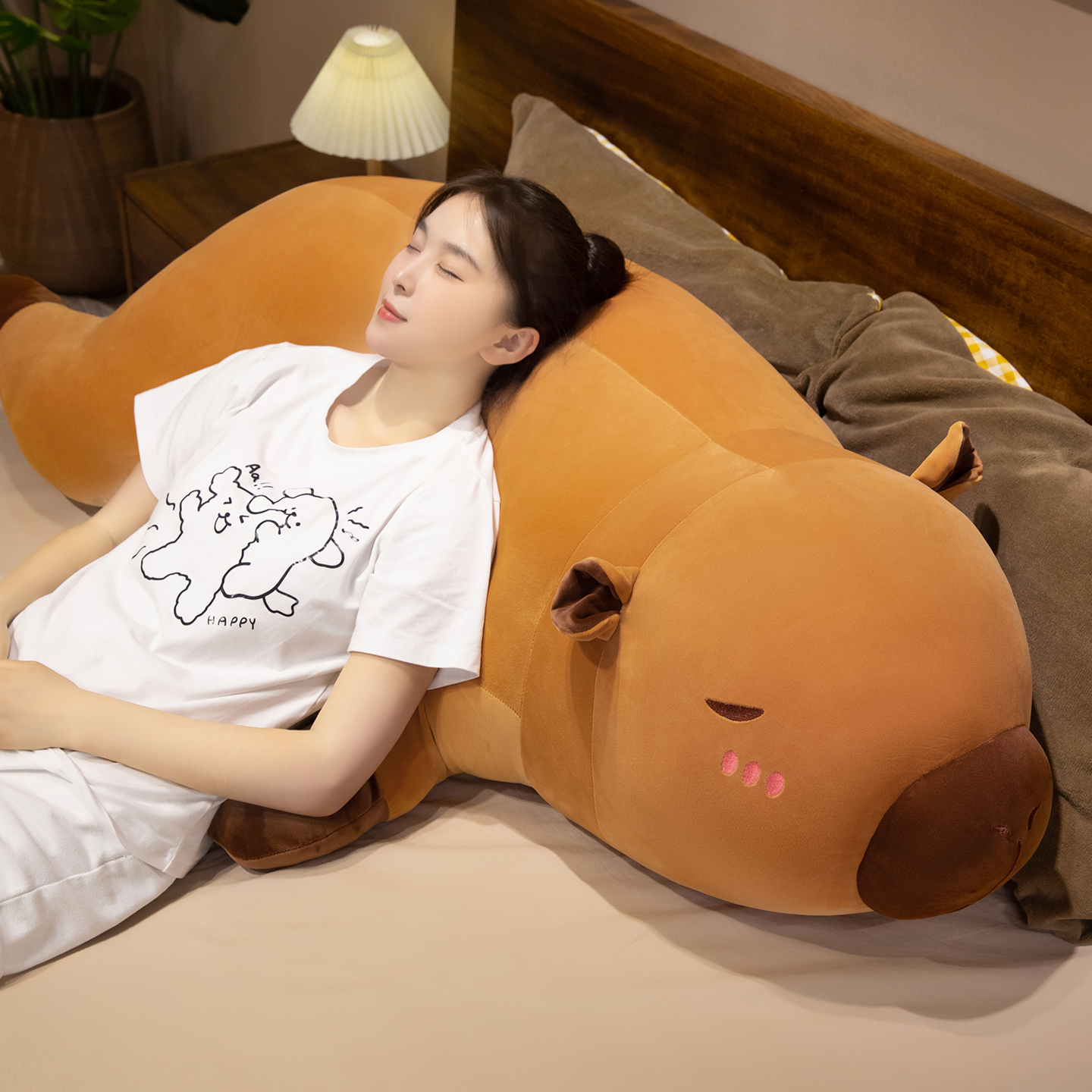 Capybara plush pillow used as a soft back support cushion on the bed, providing comfortable support for relaxing and resting