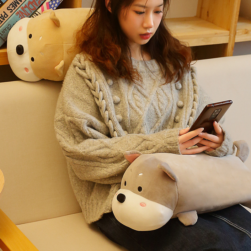 Gray lying dog plush pillow placed on a sofa for lap support, soft and cozy cushion ideal for relaxing, holding, and everyday comfort at home