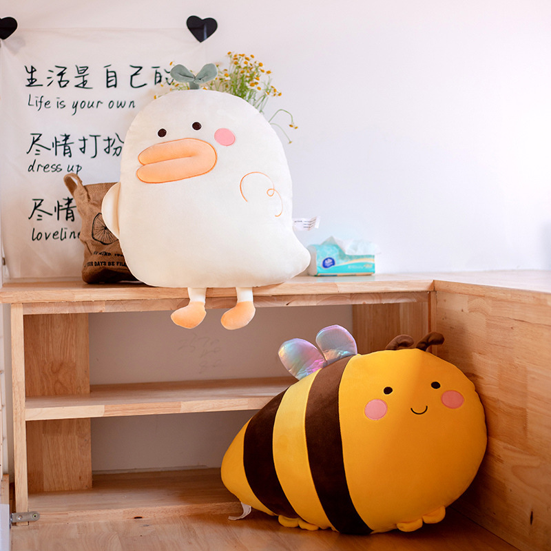 Duck and bee plush pillows on a wooden shelf, soft and cozy cushions for home decor and relaxing spaces