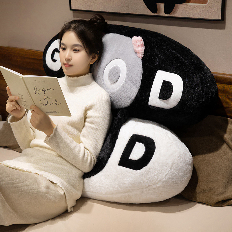 GOOD cat plush pillow used as a soft backrest cushion for reading, providing comfortable support on sofa or bed in a cozy home setting