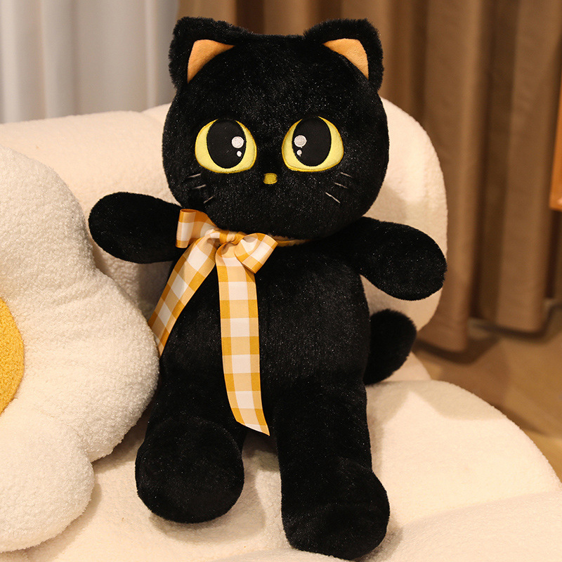 Black cat plush toy with ribbon detail on sofa, soft stuffed animal for cuddling, relaxing, and cozy home decor