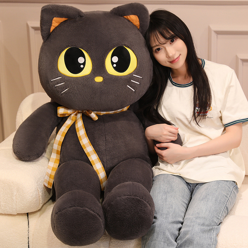 Cat plush toy with ribbon detail on sofa, soft stuffed animal ideal for cuddling, relaxing, and cozy home decor