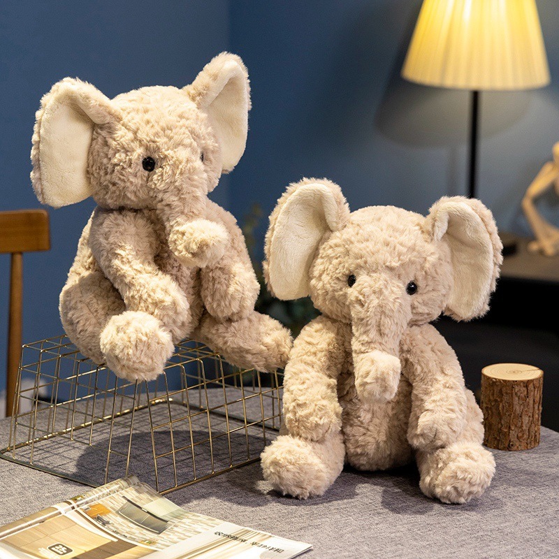 Cute elephant plush toy with soft fluffy texture in a sitting pose, displayed as cozy home decor on a tabletop setting