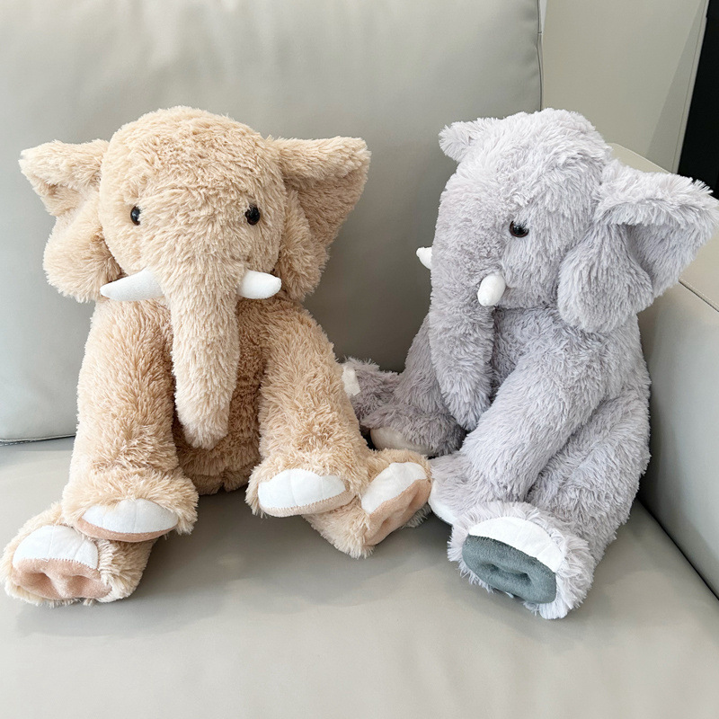 Elephant plush toys in brown and gray sitting on a sofa, soft cuddly stuffed animals for cozy home decor