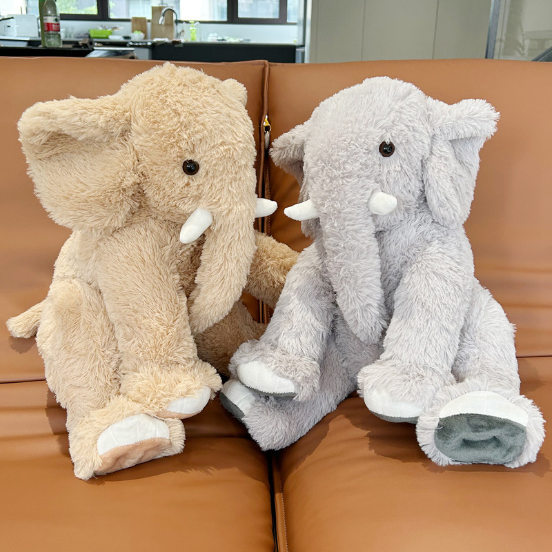 Elephant plush toys in brown and gray sitting on a sofa, soft cuddly stuffed animals for cozy home decor