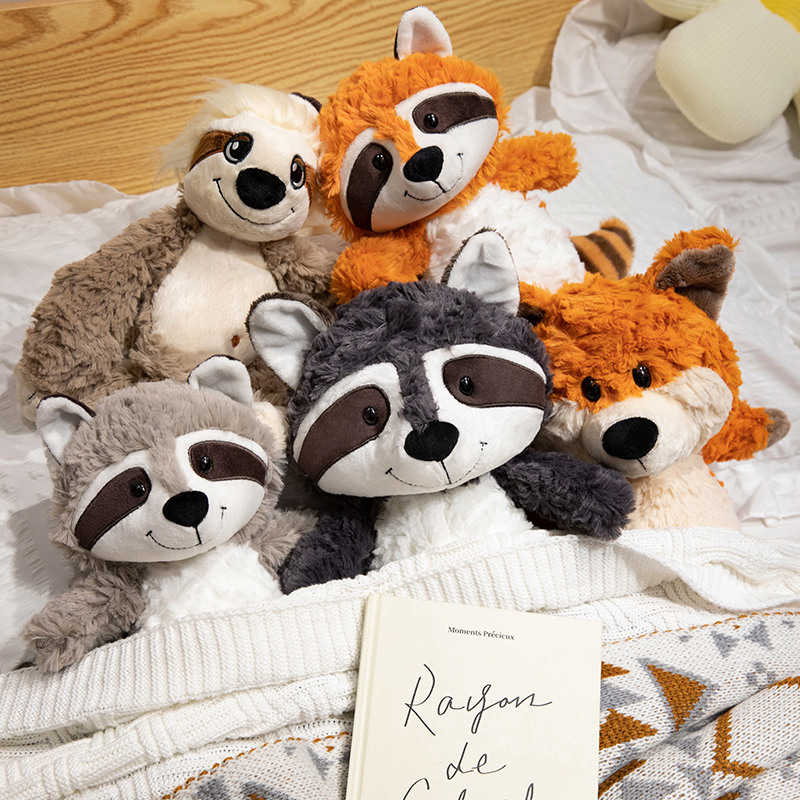 Forest animal plush toys fox raccoon and sloth soft stuffed animals on bed for cozy relaxing atmosphere