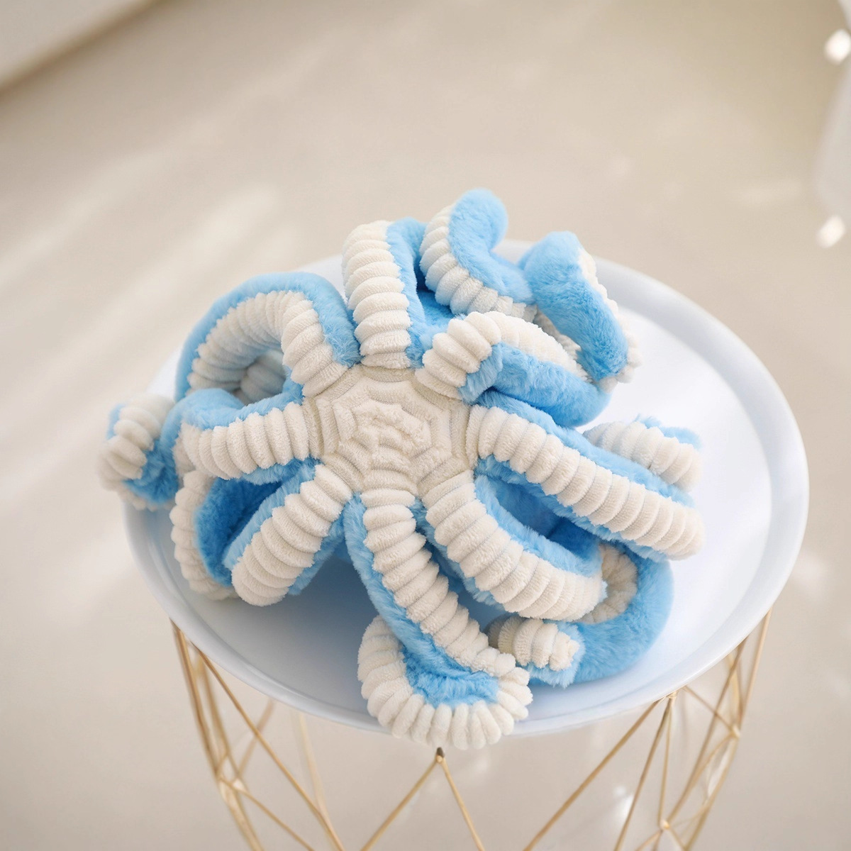 Bottom view of octopus plush toy showing soft fabric and curly tentacles, highlighting texture and flexible design details