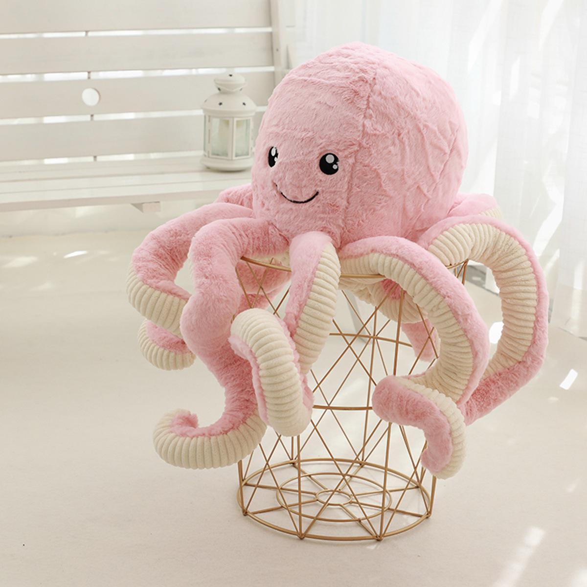 Large pink octopus plush toy draped over a table, highlighting long soft tentacles and cuddly plush texture in a bright cozy setting