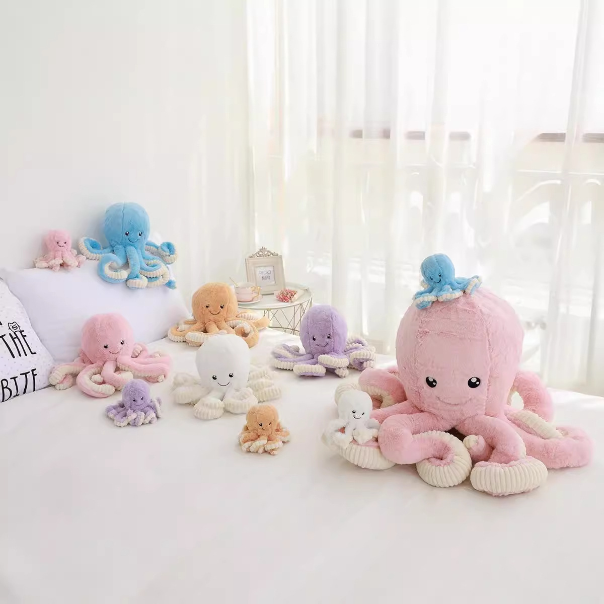 Octopus plush toys in multiple sizes and pastel colors displayed on a bed, creating a soft and cozy home decor setting