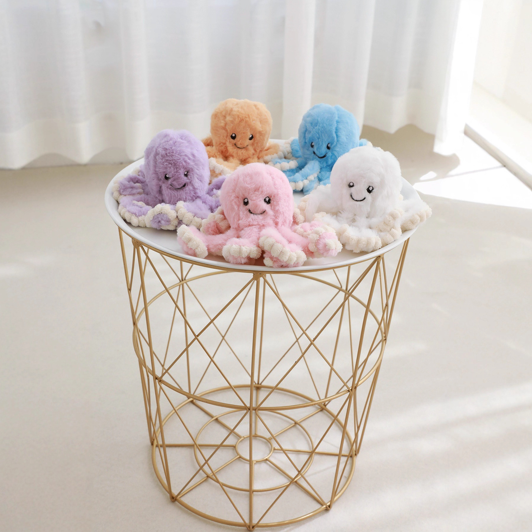 Colorful octopus plush toys in multiple shades displayed on a round table, showing soft texture and variety of color options for cute home decor