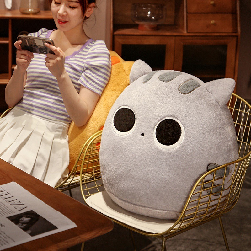 Gray round cat plush pillow used as a soft seat cushion on chair, cozy and comfortable for relaxing