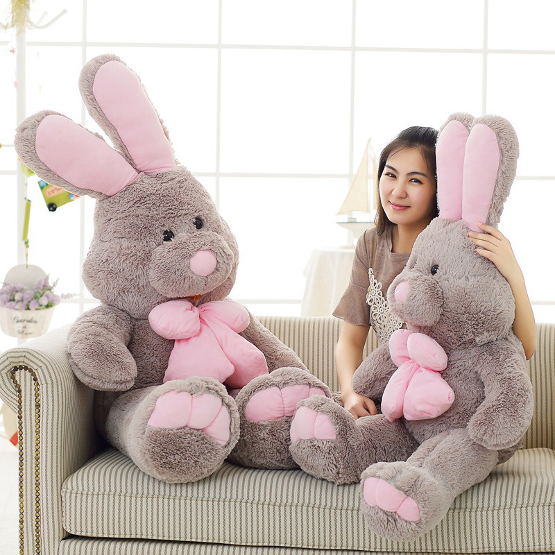 Rabbit plush toys with soft gray fabric and pink bows placed on a sofa, ideal for hugging, relaxing, and adding a cozy touch to living spaces
