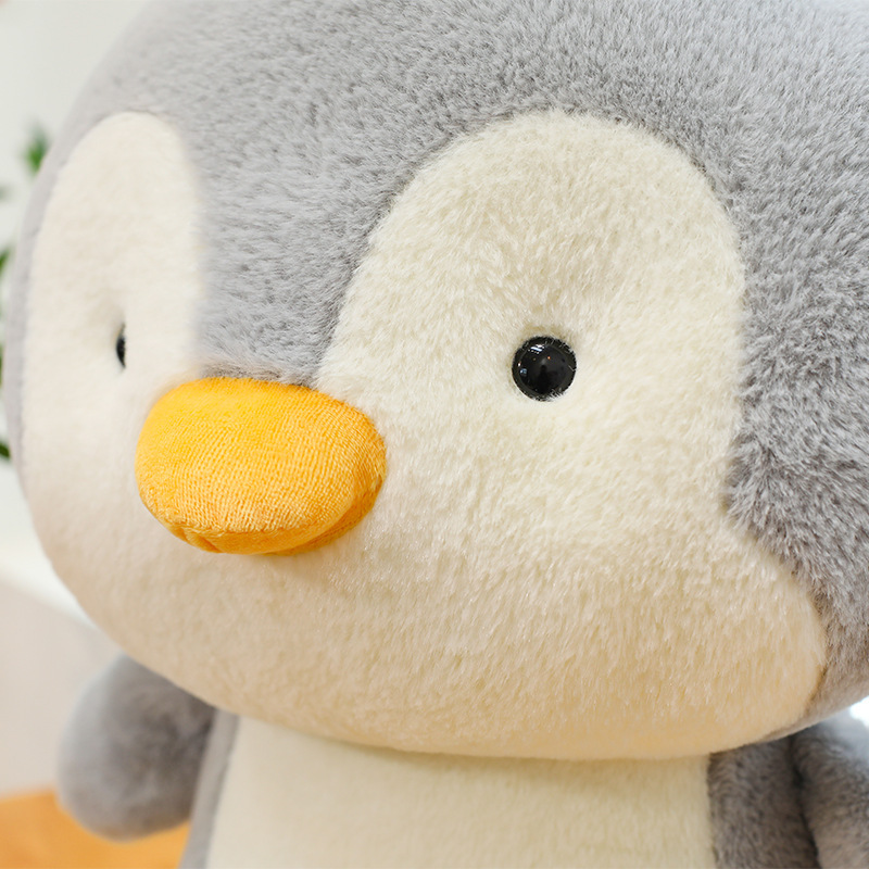 Penguin plush toy close-up with soft smooth fabric, featuring a cute rounded face, bright eyes, and a gentle, cuddly expression