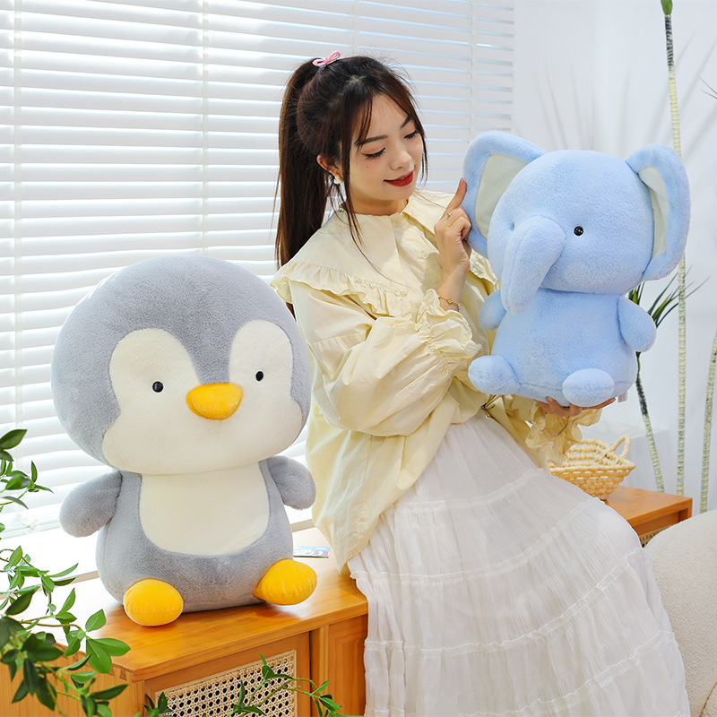 Penguin and elephant plush toys in soft plush fabric displayed in a cozy indoor setting, highlighting their rounded shapes, smooth texture, and cuddly feel for everyday comfort