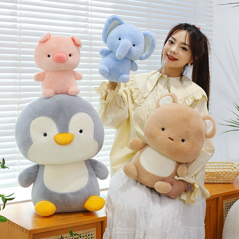 Animal plush toys featuring pig, elephant, bear, and penguin in soft plush fabric, arranged in a cozy indoor setting to highlight their cute rounded design and cuddly feel