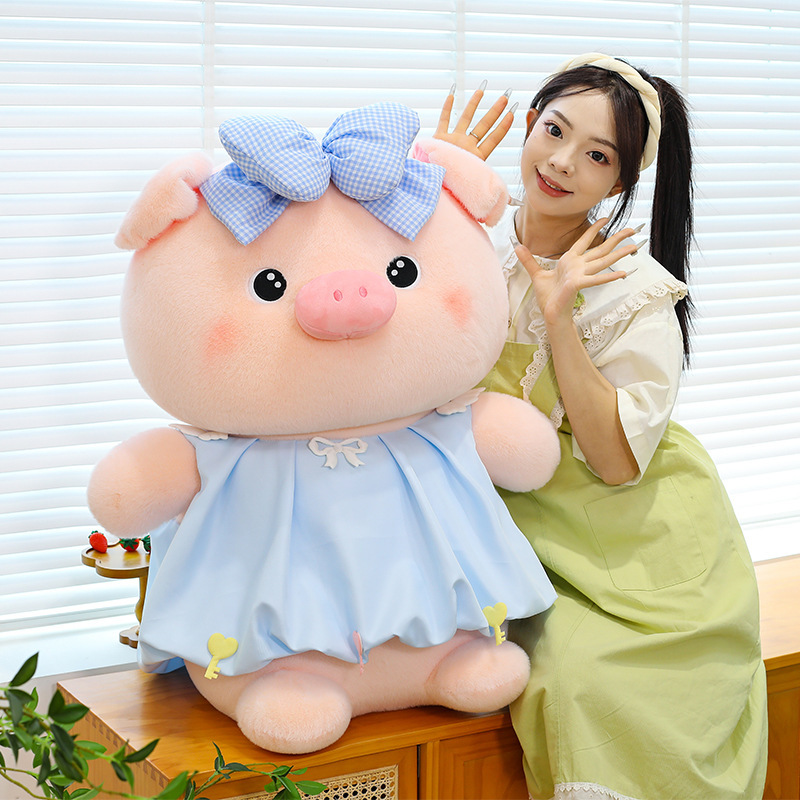 Bubble pig plush toy in blue dress with bow detail placed on cabinet, soft plush fabric and rounded design, suitable for display and cozy room styling
