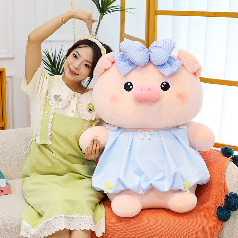 Bubble pig plush toy in blue dress with bow detail placed on sofa, soft plush fabric and rounded design, ideal for cuddling and cozy living room decor