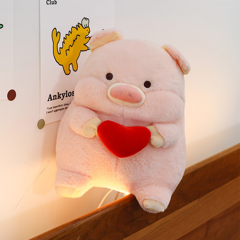 Pig plush toy with red heart design soft stuffed animal pillow placed on bedside with warm ambient lighting