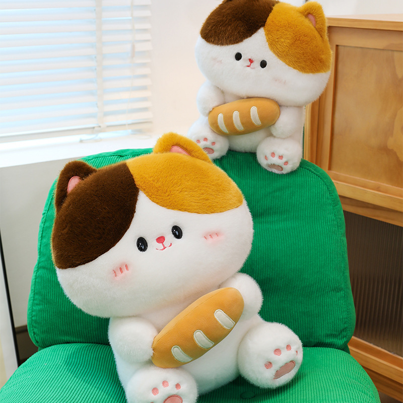 Baguette cat plush toy placed on green chair with layered arrangement showing soft plush texture rounded shape and cozy indoor setting