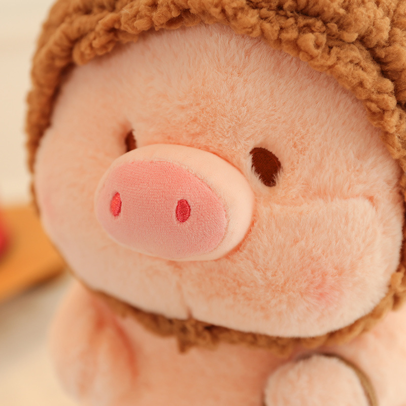 Pig plush toy in animal costume close up showing soft plush texture, embroidered facial features, and smooth fabric finish