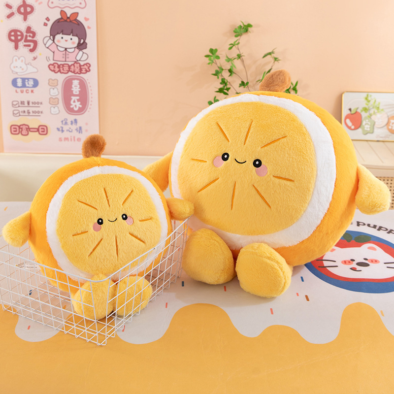 Orange plush pillow in smaller size placed in a storage basket alongside a larger version, featuring smiling fruit design, soft cushion for cozy home decor