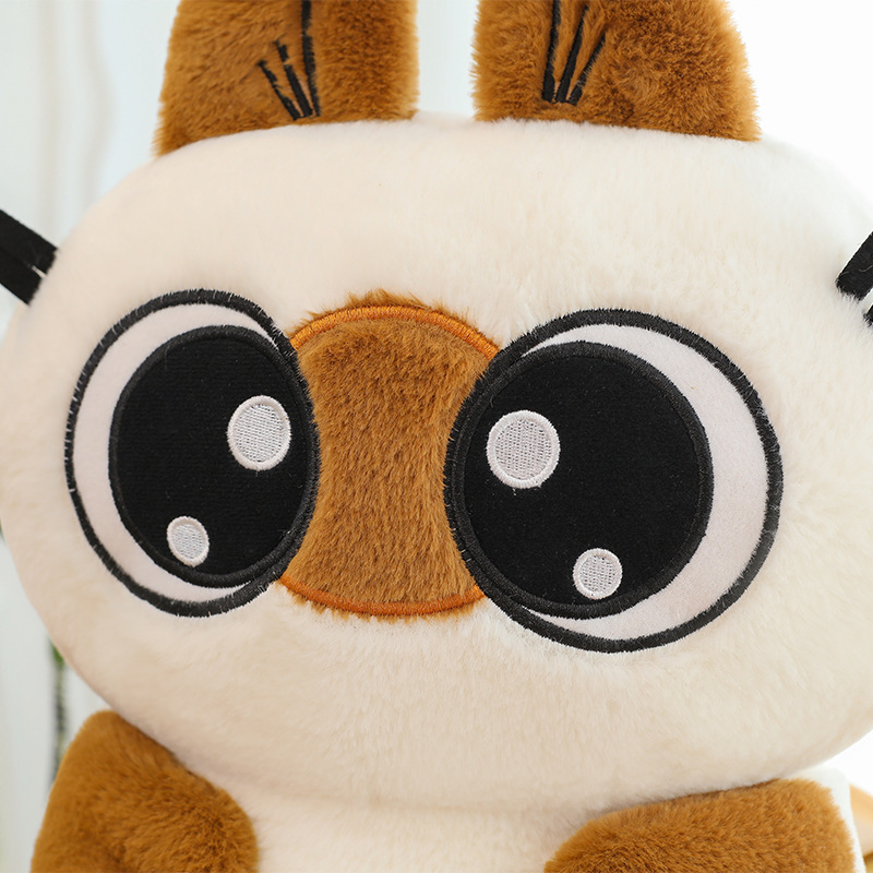 Close up of Siamese cat plush toy face with big embroidered eyes and soft plush texture, highlighting cute design details
