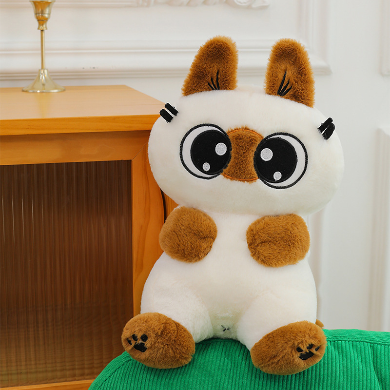 Siamese cat plush toy with big eyes and soft plush fabric, placed on a chair in a cozy home setting, perfect for decoration and cuddling