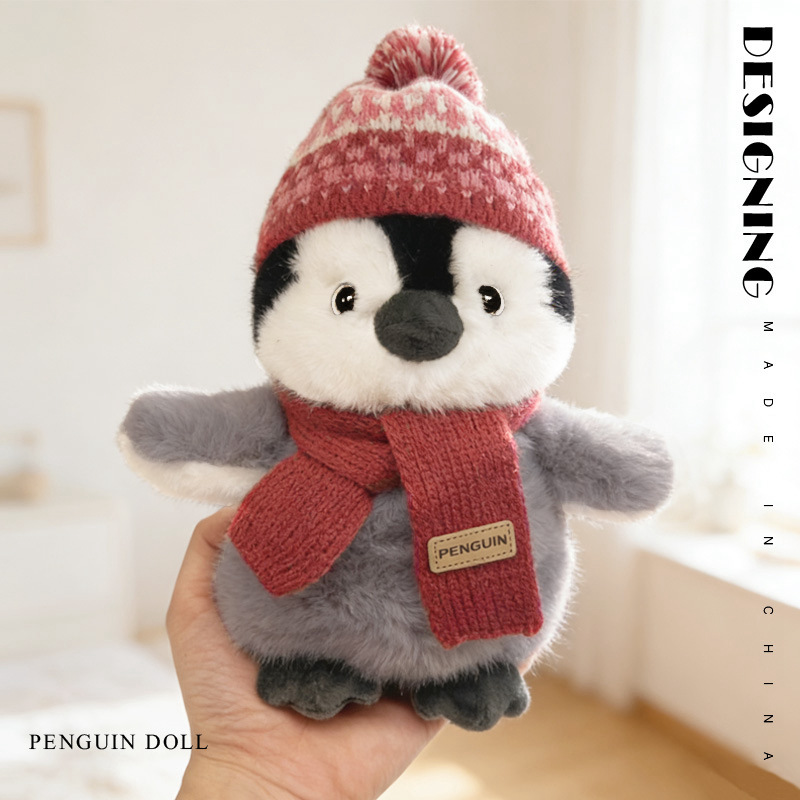 Winter penguin plush toy in hand with red scarf soft stuffed animal size reference and close up product view