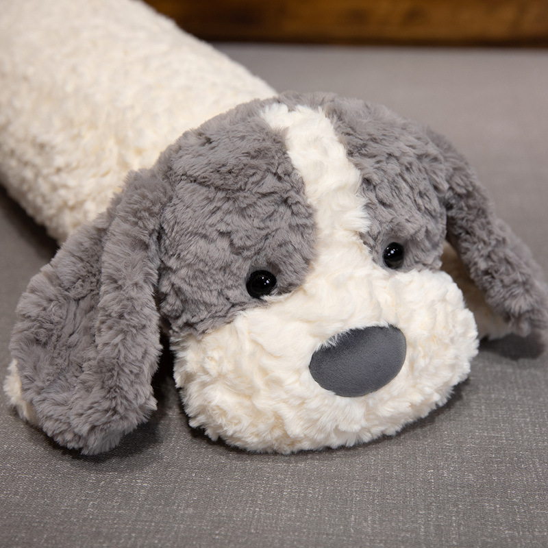 Gray lying dog long plush pillow close up showing soft plush texture, rounded shape and detailed face design
