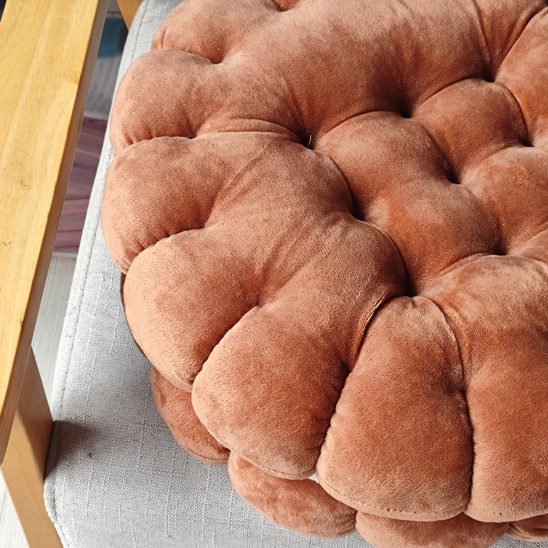 Close-up of brown sandwich cookie plush cushion on sofa, soft textured fabric floor pillow for cozy seating