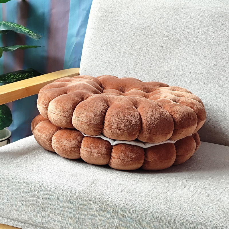Brown sandwich cookie plush cushion on sofa, soft biscuit floor pillow for seating and cozy home decor
