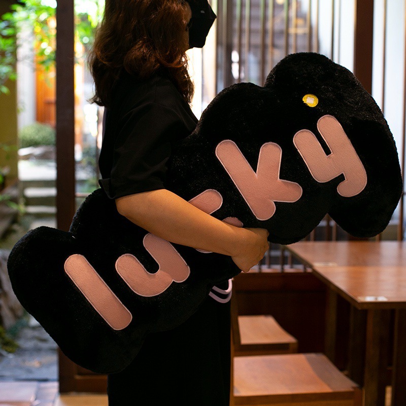 Black lucky plush pillow with soft fabric and raised letter design, comfortable long cushion for bed or sofa