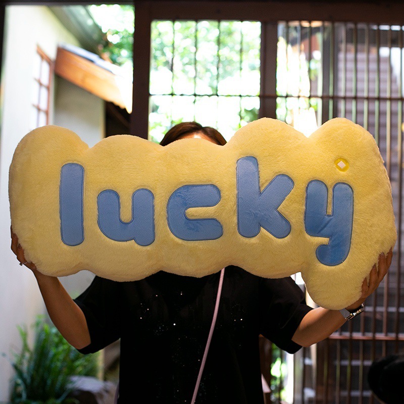 Yellow lucky plush pillow with bold letter design, soft long cushion for bed, sofa, and cozy spaces