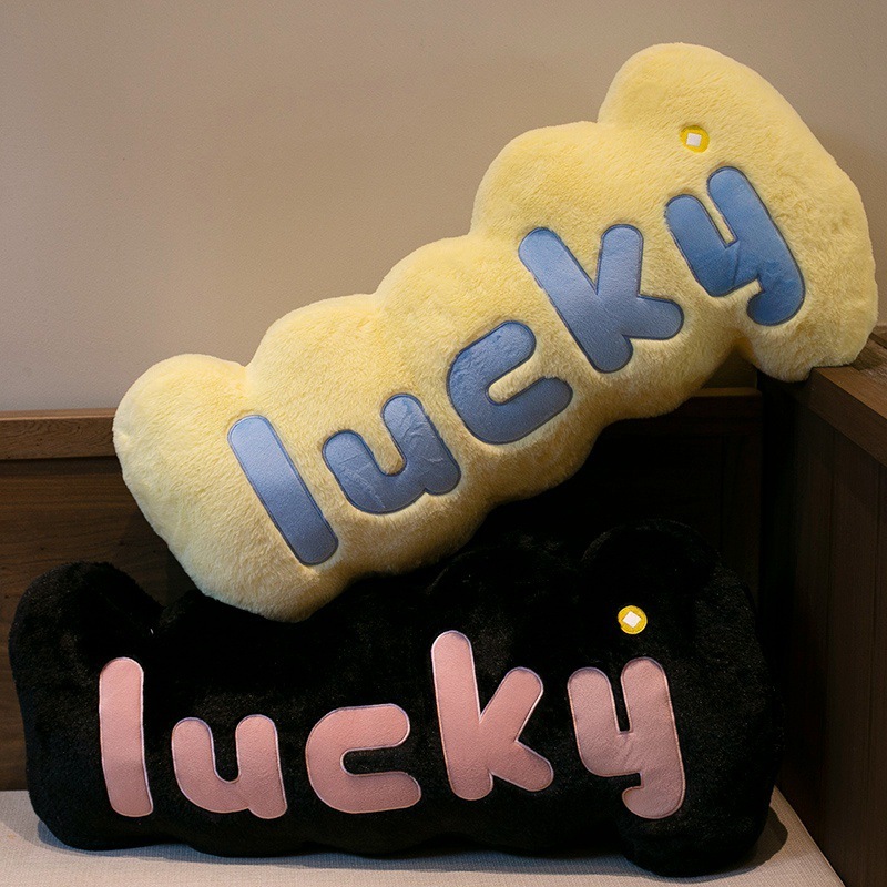 Lucky plush pillows in yellow and black stacked together, soft letter cushions for stylish home decor