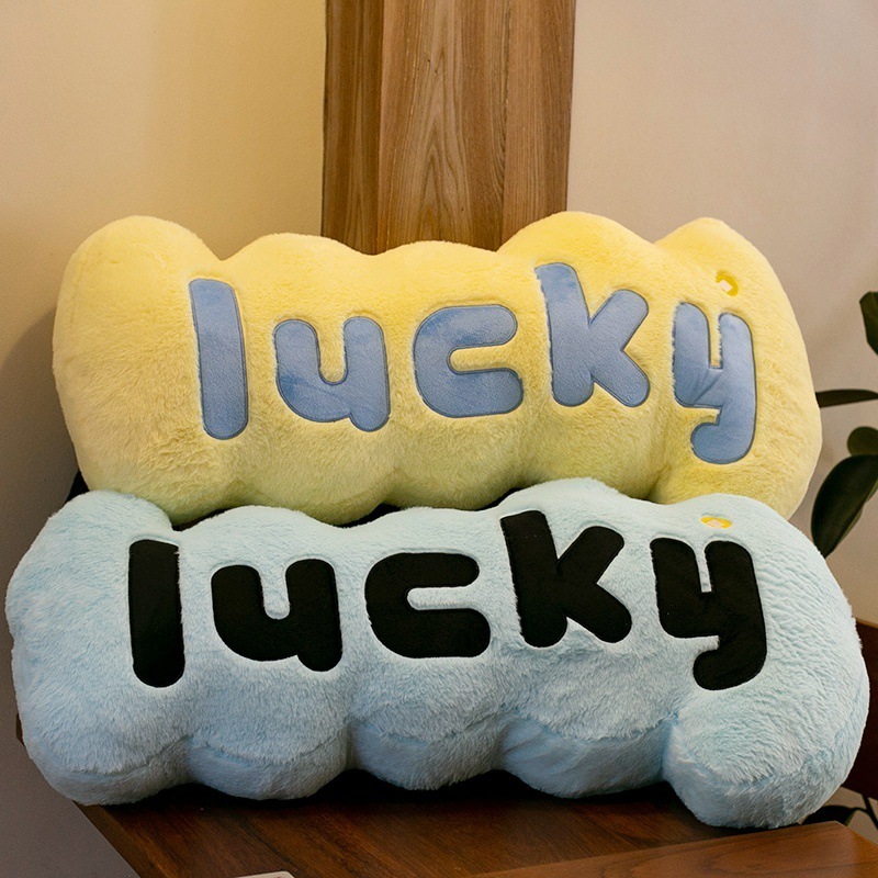 Lucky plush pillows in blue and yellow stacked on chair, soft decorative cushions for cozy home decor