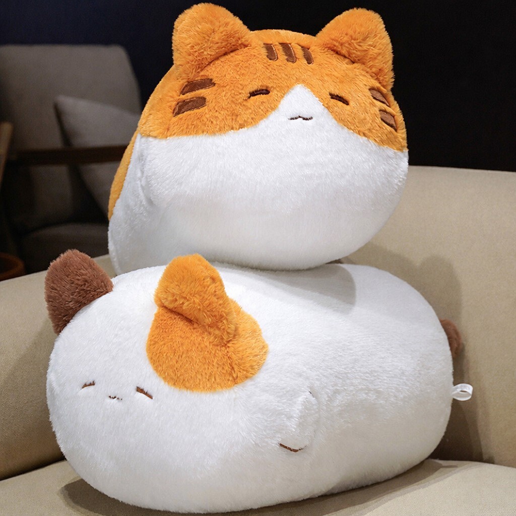 Cartoon cat plush pillow in orange and calico designs stacked on a sofa, soft rounded cushion for cozy decor and relaxing spaces