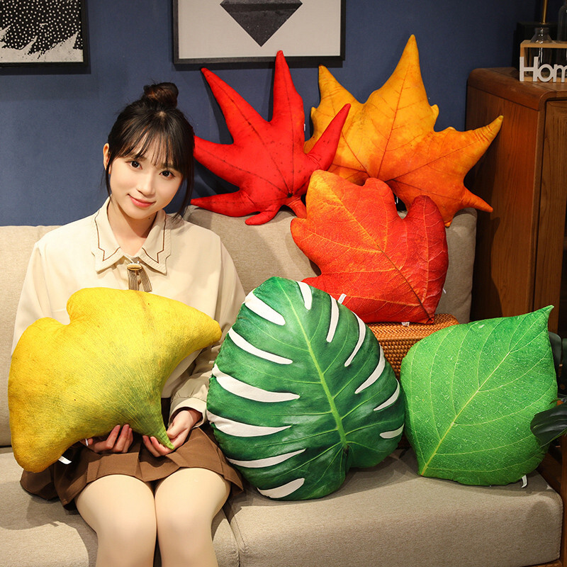 Leaf plush pillow in various designs including monstera, maple, and ginkgo, displayed on a sofa for cozy home decor and relaxing use