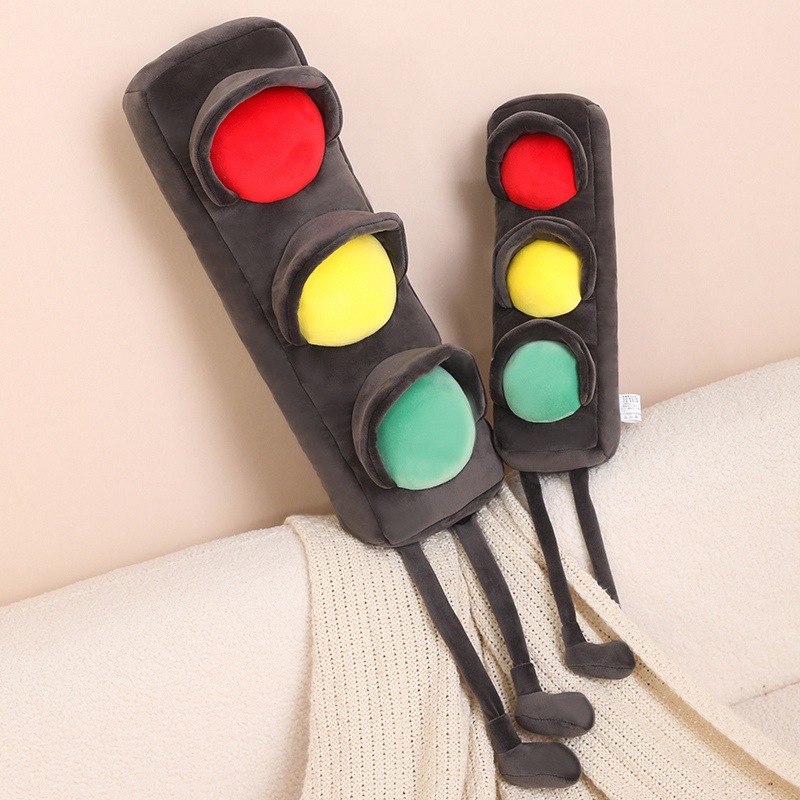 Traffic light plush pillows leaning on a sofa, long soft cushions with red yellow green design and dangling legs, playful home decor for comfort and relaxation