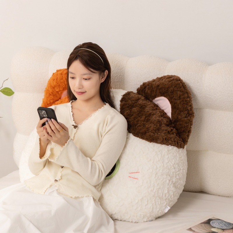 Cartoon cat head plush pillow used as a soft backrest cushion on bed, supportive and comfortable for relaxing, reading, or everyday lounging